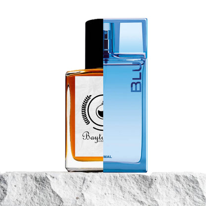 "Two perfume bottles are displayed side by side on a light stone surface."
"On the left, an amber bottle with a black cap, the Baytulkenz inspired version of Blu by Ajmal."
"The amber bottle has a sleek, modern design with a deep, warm color and a contrasting black cap."
"On the right, a sea blue bottle representing the original Blu by Ajmal, with a fresh, vibrant hue."
"The sea blue bottle features a clean, elegant shape and a minimalist label."