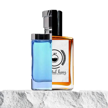 "A split image features two perfume bottles displayed side by side on a light stone surface."
"On the left, a blue bottle with a silver cap, labeled Desire Blue by Alfred Dunhill."
"The Desire Blue bottle has a sleek, contemporary design with a vibrant blue hue and a polished silver cap, exuding sophistication."
"On the right, an amber bottle, the Baytulkenz inspired version of Desire Blue by Alfred Dunhill."
"The amber bottle has a warm, rich color with a minimalist design, featuring the Baytulkenz logo."