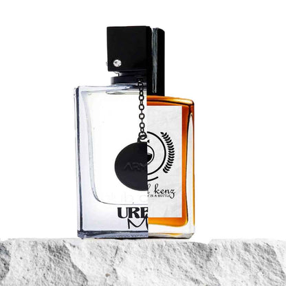 "A split image features two perfume bottles displayed side by side on a light rock background."
"On the left, a clear bottle with a black cap, labeled Club de Nuit Urban Man by Armaf."
"The Club de Nuit Urban Man bottle has a clean, modern design with a transparent look and a bold black cap."
"On the right, an amber bottle, the Baytulkenz inspired version of Club de Nuit Urban Man by Armaf."
"The amber bottle has a warm, rich color with a sleek, refined design and the Baytulkenz logo on the label."